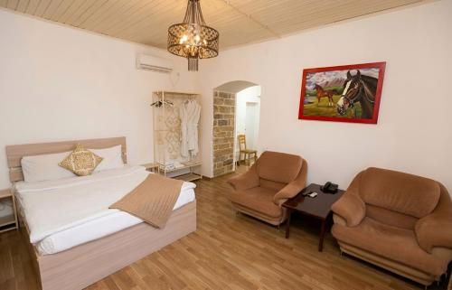 a bedroom with a bed and two chairs in it at Green Garden Hotel in Baku