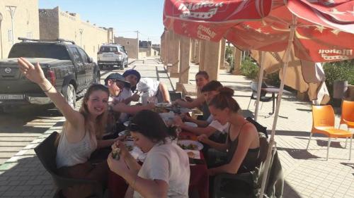 a group of people sitting at a table eating food at Chez zakaria guest house in Merzouga