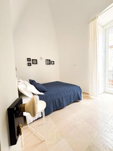 a white bedroom with a bed and a chair at Dimora Veneziani in Bisceglie