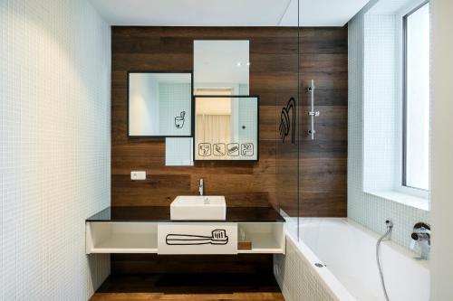 a bathroom with a sink and a mirror and a tub at Pytloun Imperial Design Suites in Liberec