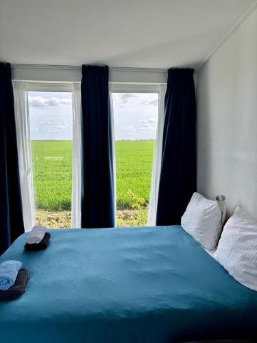a bedroom with a blue bed and a window at Waegen Uus in Wolphaartsdijk