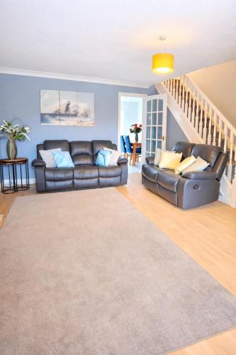 a living room with a leather couch and stairs at Bedlington 3 bed house in Bedlington