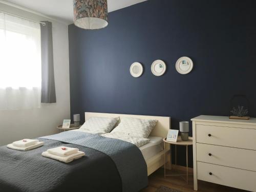 a blue bedroom with a bed and three plates on the wall at FoBala Apartman in Balatonföldvár