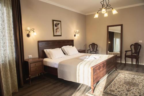 a bedroom with a bed and two chairs and a mirror at Hotel Vila Bregu in Tirana