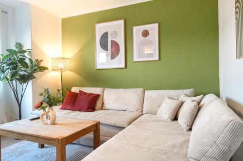 a living room with a white couch and a green wall at Ferienwohnung Elbhang mit Stellplatz in Königstein an der Elbe