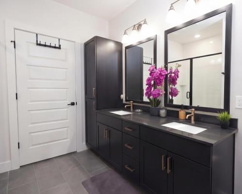 a bathroom with a black vanity with two sinks and a mirror at Downtown Dallas ELLUM OASIS with Balcony, Pool, Rooftop Deck, Gym, Queen Bed, King Sleeper Sofa, 2 Twin Sleeper Chairs, and Parking Garage in Dallas