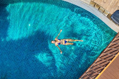 a person swimming in a swimming pool at The Taksim Royal Beachfront Resort in Patong Beach