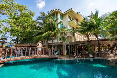 a woman standing on a bridge over a swimming pool at The Taksim Royal Beachfront Resort in Patong Beach