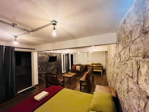 a room with a stone wall and a bed and a couch at Yolcehuikalli - Loft Cuetzalan in Cuetzalán del Progreso