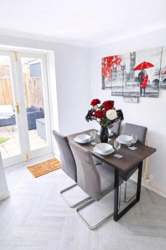 a dining room with a table with chairs and a vase of flowers at Bedlington 3 bed house in Bedlington