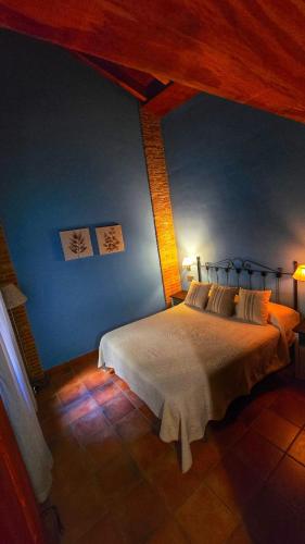 a bedroom with a bed with a blue wall at APARTAMENTOS La Colmena APT- 2 - AT-CC-00248 in Gata