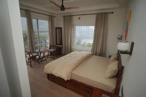 a bedroom with a bed and a table and windows at Sanobar Home Stay in Bhīm Tāl