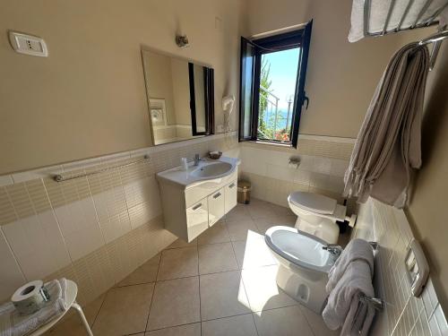 a bathroom with a sink and a toilet and a mirror at Hotel Normanni in Praia a Mare