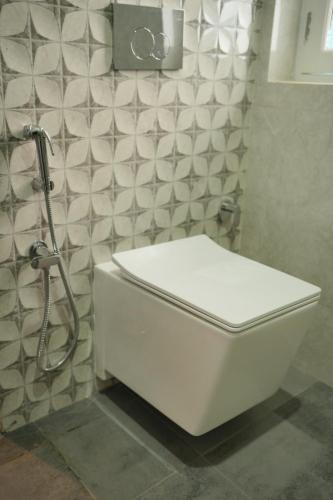 a white toilet in a bathroom with a tiled wall at Sanobar Home Stay in Bhīm Tāl