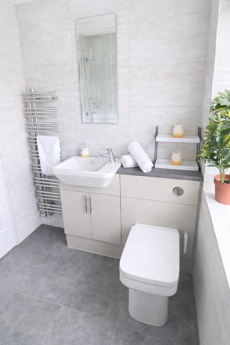 a white bathroom with a toilet and a sink at Bedlington 3 bed house in Bedlington