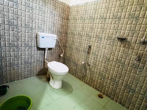 a bathroom with a toilet in a tiled wall at Hotel Sundaram in Deoghar