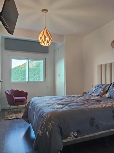 a bedroom with a bed and a chair and a window at Mabel House Sierra de Gredos in Mijares