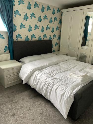a bedroom with a bed with blue and white wallpaper at Selsey Home in Selsey