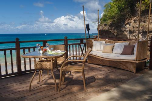 a table and chairs on a deck with the ocean at Cap Maison Resort & Spa in Cap Estate
