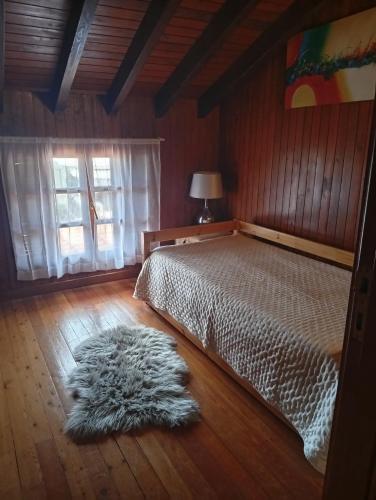 a bedroom with a bed and a rug on the floor at CASA DE MADEIRA E PEDRA in Afife
