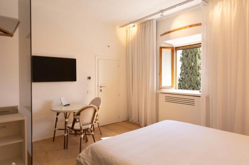 a bedroom with a bed and a table and a window at Terra d'Ombra Bed&Breakfast in San Gimignano