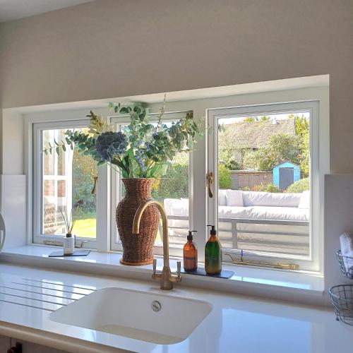 a kitchen with a window and a sink and a vase with flowers at The Homestead -Cosy Cottage for 2 in Wells next the Sea