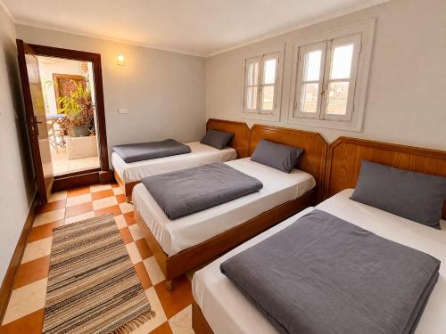 a room with three beds and a window at Dahab Hostel in Cairo