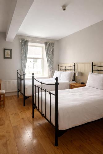 two beds in a bedroom with a window at The Highlands Hotel in Glenties