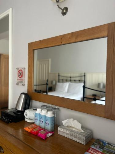 a bathroom counter with a mirror and some bottles of bleach at The Highlands Hotel in Glenties