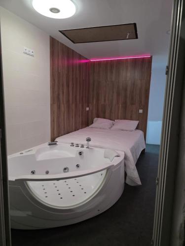 a bathroom with a bath tub next to a bed at Mabel House Suites in Mijares