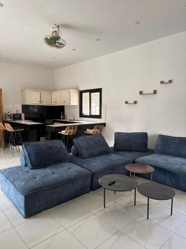 a living room with blue couches and a kitchen at Chez Sira in Warang