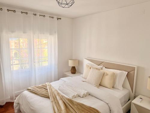 a white bedroom with a large bed with white pillows at Cantinho do Castelo in Bragança