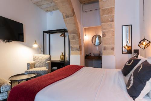 a bedroom with a bed and a chair and a mirror at Pjazza Suites Boutique Hotel by CX Collection in Siġġiewi