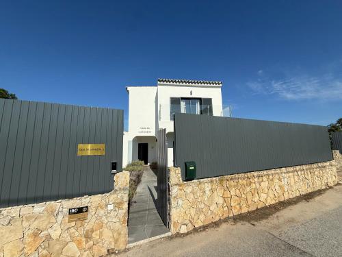 a white building with a stone wall in front of it at Casa Da Laranjeira- Serene 4Bedroom 4Bath Pool & Garden Villa, 10 mins to Vilamoura Marina in Quarteira
