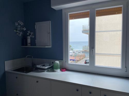 a blue kitchen with a sink and a window at Hotel Miramare in Savona
