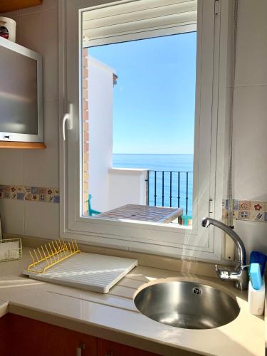a kitchen sink with a window with a view of the ocean at Ático dúplex - 1ª Linea playa in Adra