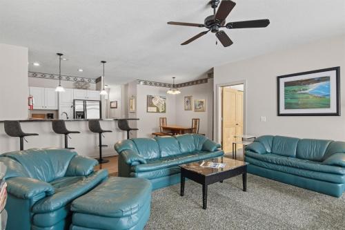 a living room with blue couches and a kitchen at Skier's Slopeside Haven in Bellaire