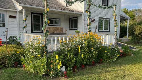 a house with a garden of flowers in front of it at Sunset View Centennial Farm in Mancelona