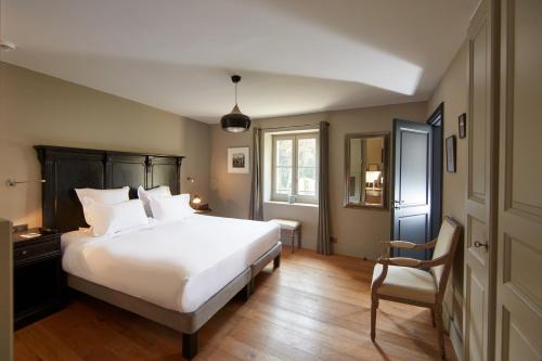 a bedroom with a large white bed and a chair at Domaine de Fontenille in Lauris
