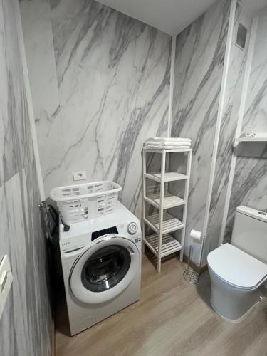 a washing machine in a bathroom with a toilet at O Repouso in Lalín
