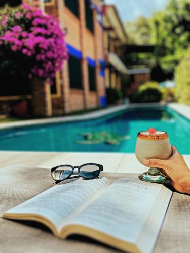a person holding a book with a cup of coffee and glasses at Hotel Zaragoza in Tepoztlán