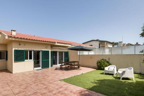 a patio with a table and chairs and an umbrella at Mindelo Beach House in Vila Chã