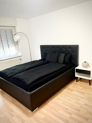 a large black bed in a room with a lamp at Ferienwohnung Sophie in Weil am Rhein
