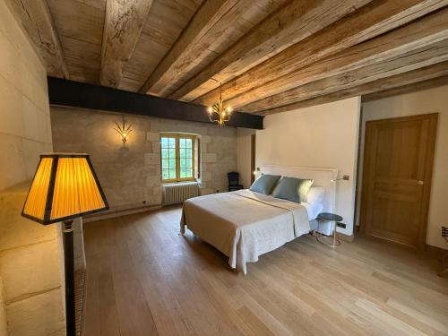 a bedroom with a bed and a lamp and wooden ceilings at Gîte du Château des Brétignolles - Patrimoine, Piscine & Nature - Près de Chinon in Anché