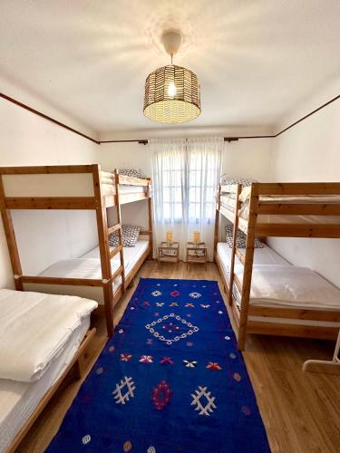 a room with three bunk beds and a blue rug at Yacumama Guesthouse in Soorts-Hossegor