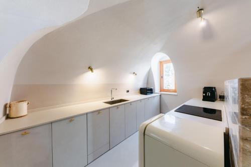 a kitchen with white cabinets and an arched ceiling at AmalfiRa Luxury Seaview Rooftop in Amalfi