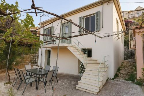 a house with a table and chairs and a staircase at Perioptron Guesthouse Ithaca in Vathi