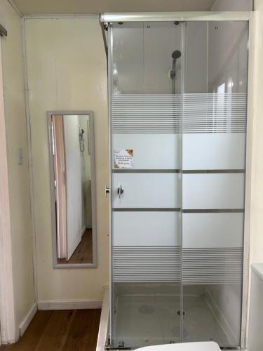 a glass shower in a bathroom with a mirror at Hostal Chucaita Puerto Cisnes in Puerto Cisnes
