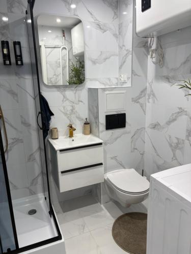 a white bathroom with a toilet and a shower at Luksusowy Apartament Giżycko in Giżycko