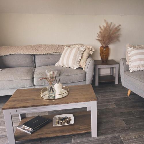 a living room with a couch and a coffee table at 19 the Coombe Charming, 2-Bedroom Family Chalet with Parking, Near Bude Beaches in Bude